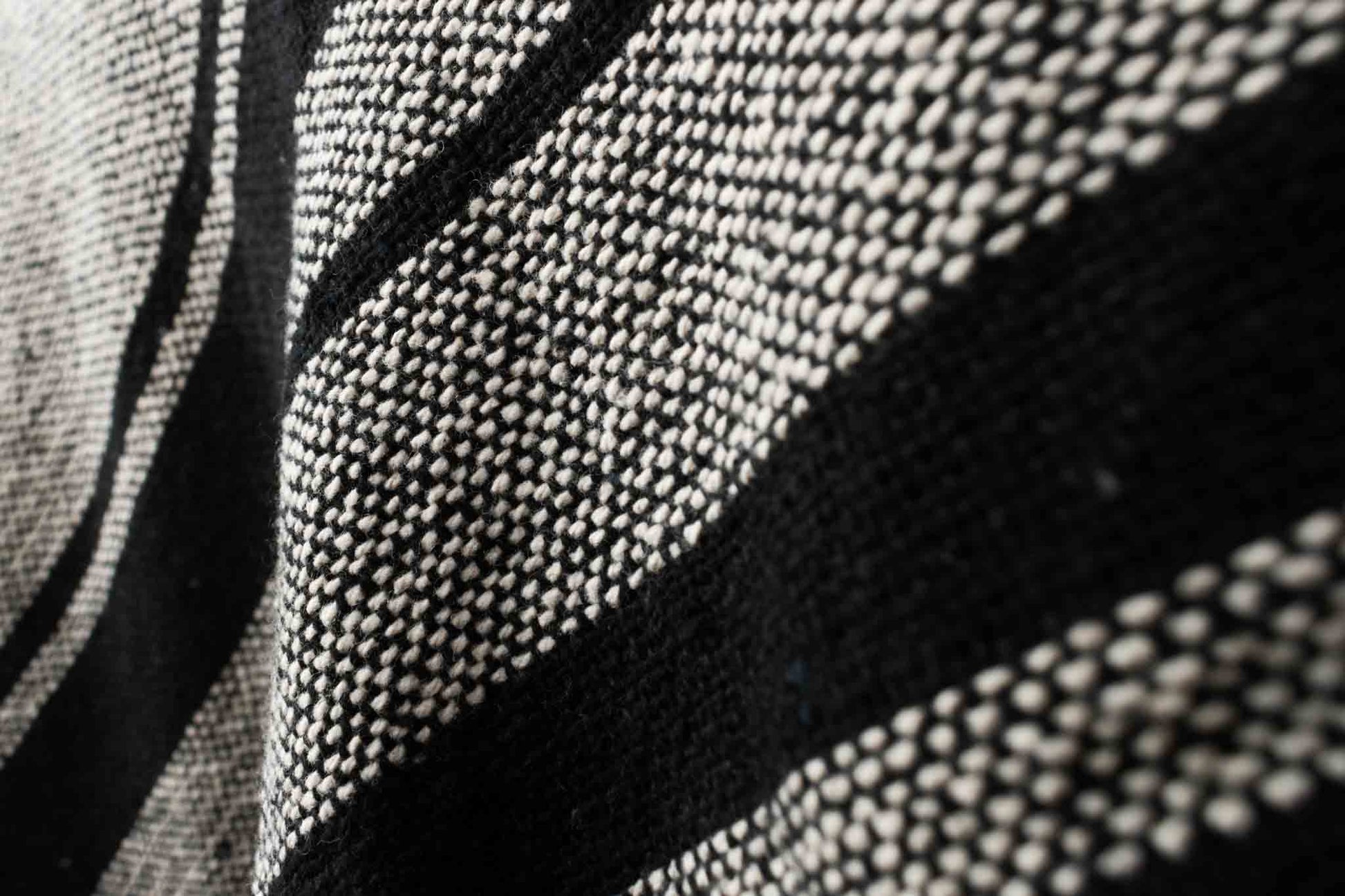 Cotton throw blanket with sand and black stripes fabric closeup.