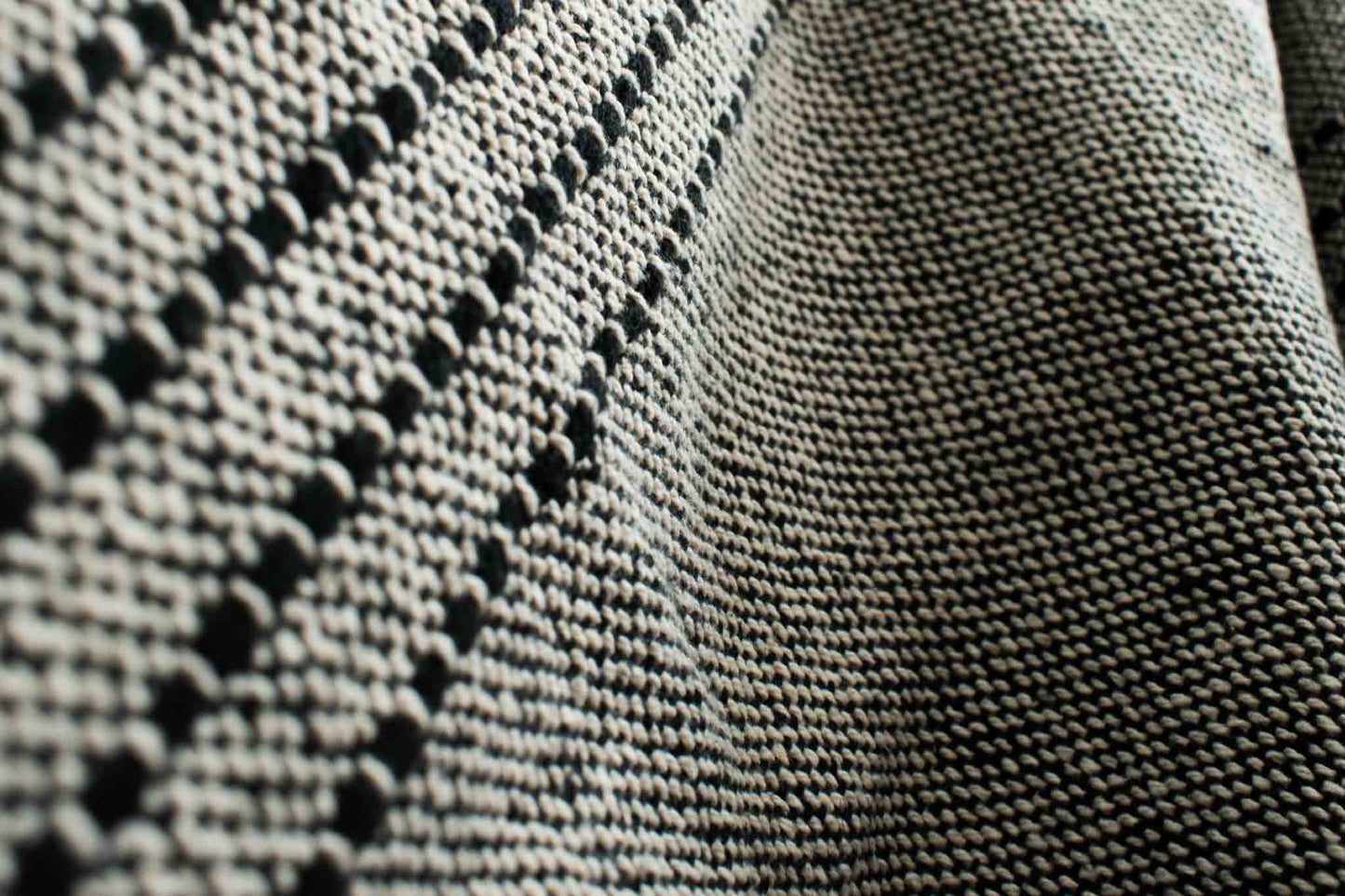 Cotton throw blanket with black and sand weaving and black ticked lines fabric closeup.