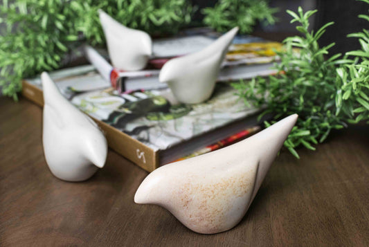 Handcrafted soapstone birds on walnut table with books and rosemary.