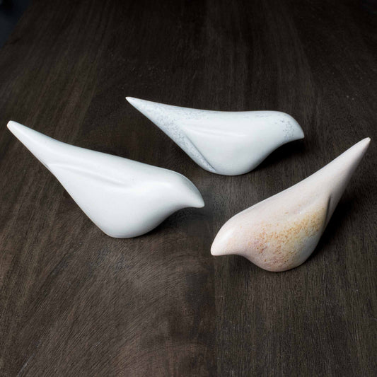 Handcrafted soapstone birds on walnut table.