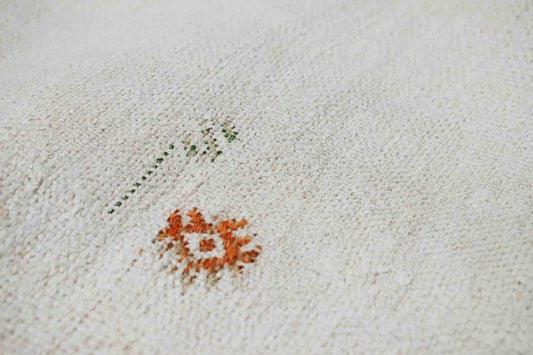 Handwoven Turkish kilim sisal pillow cover fabric in cream with orange and green design accents.