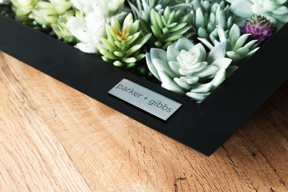 Black matte metal centerpiece tray with succulents on farmhouse table with nameplate.