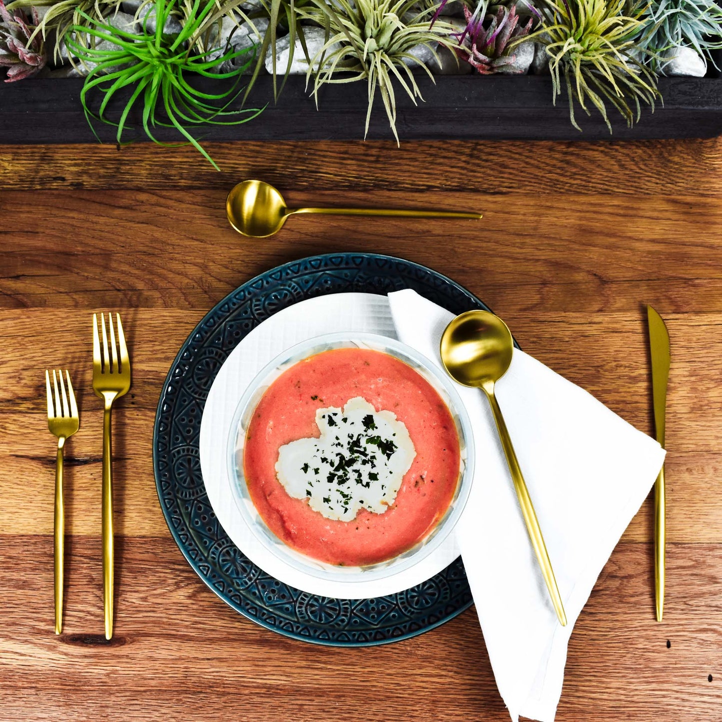 Matte brushed gold flatware set with tomato bisque soup and succulents.