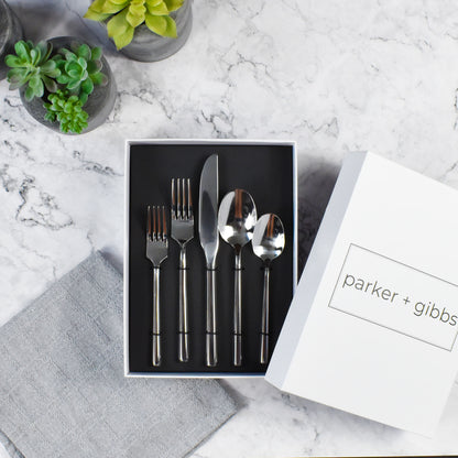 Polished silver hexagonal flatware in custom box on marble countertop with succulents in concrete planters.