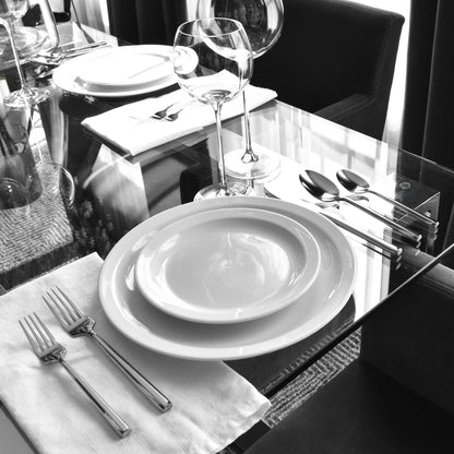Shiny polished stainless hexagonal flatware set on modern dining table with wine glasses and white dinnerware.