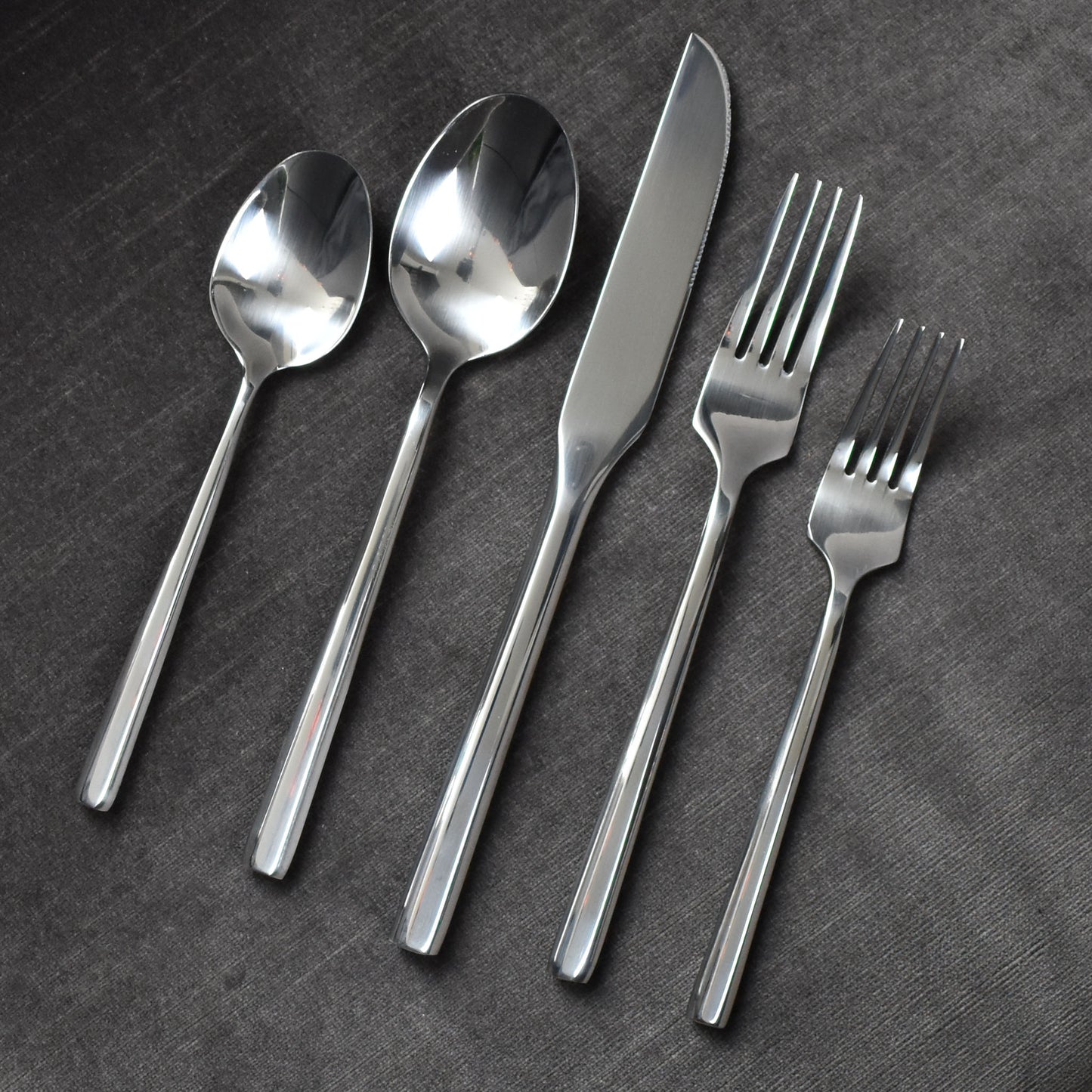 Polished silver hexagonal flatware on dark grey background.