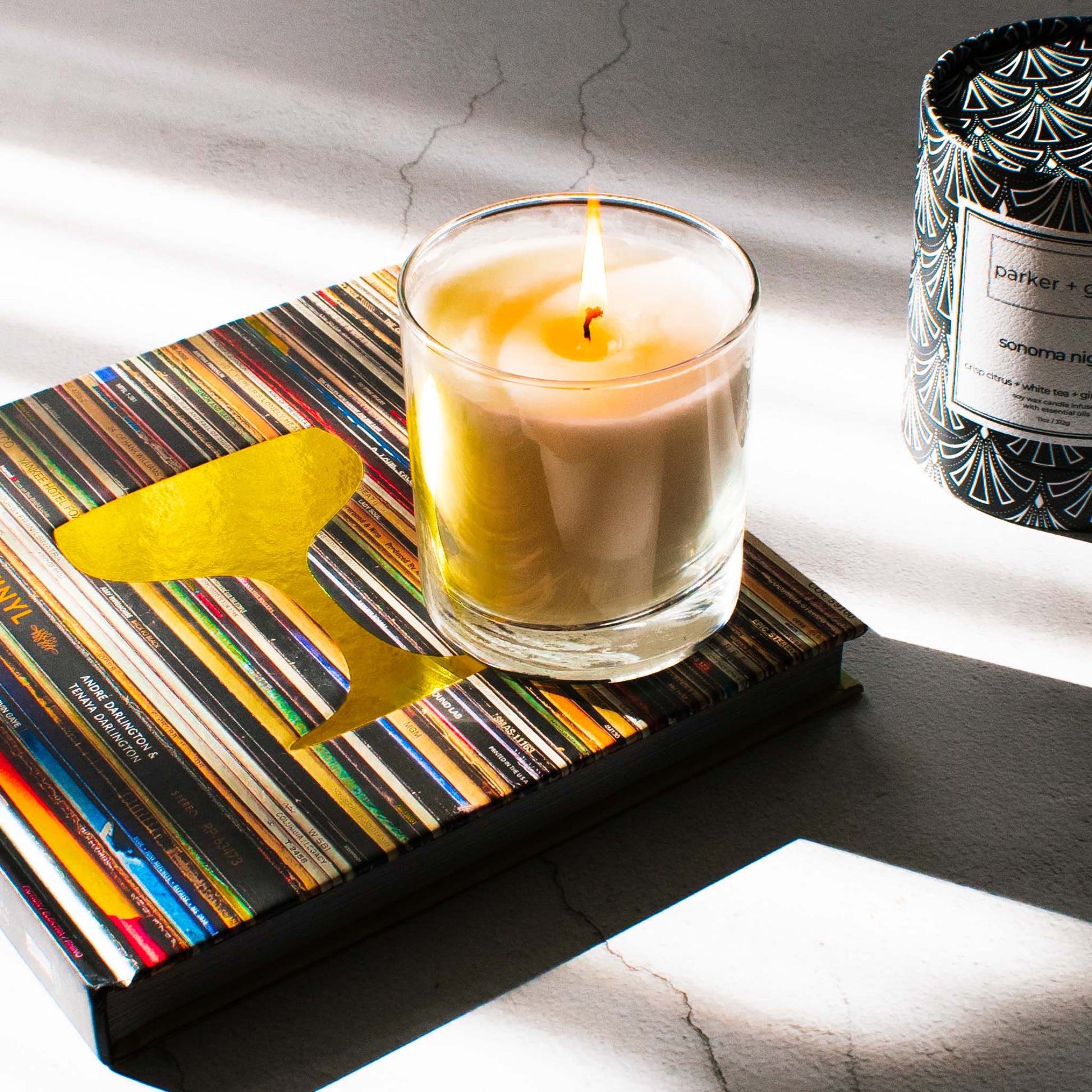 Luxury scented soy wax blend  candle on Booze and Vinyl book on limestone table.