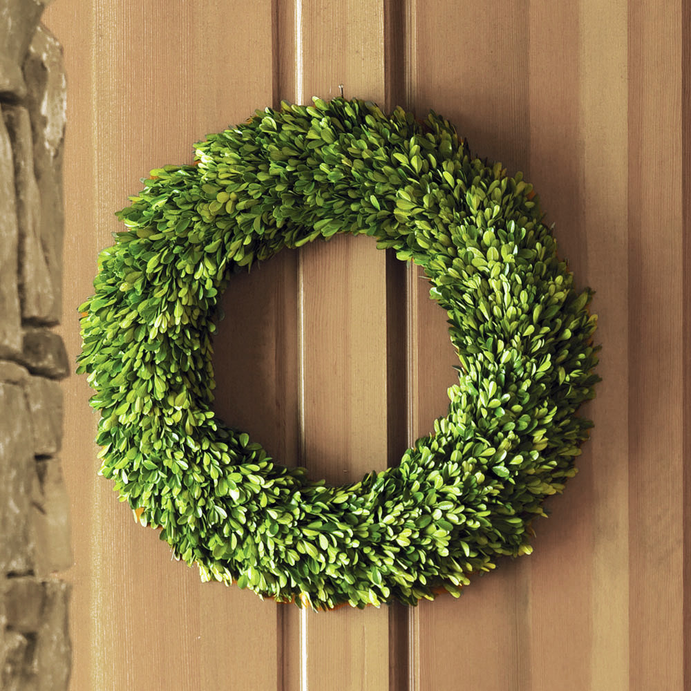 24" round preserved boxwood wreath hanging on wooden door.