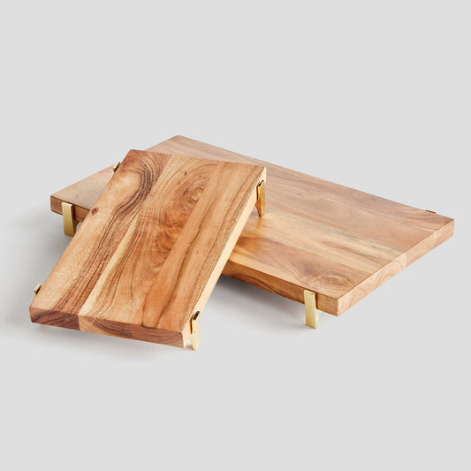 Acacia wood rectangular serving board, stacked, with gray background.
