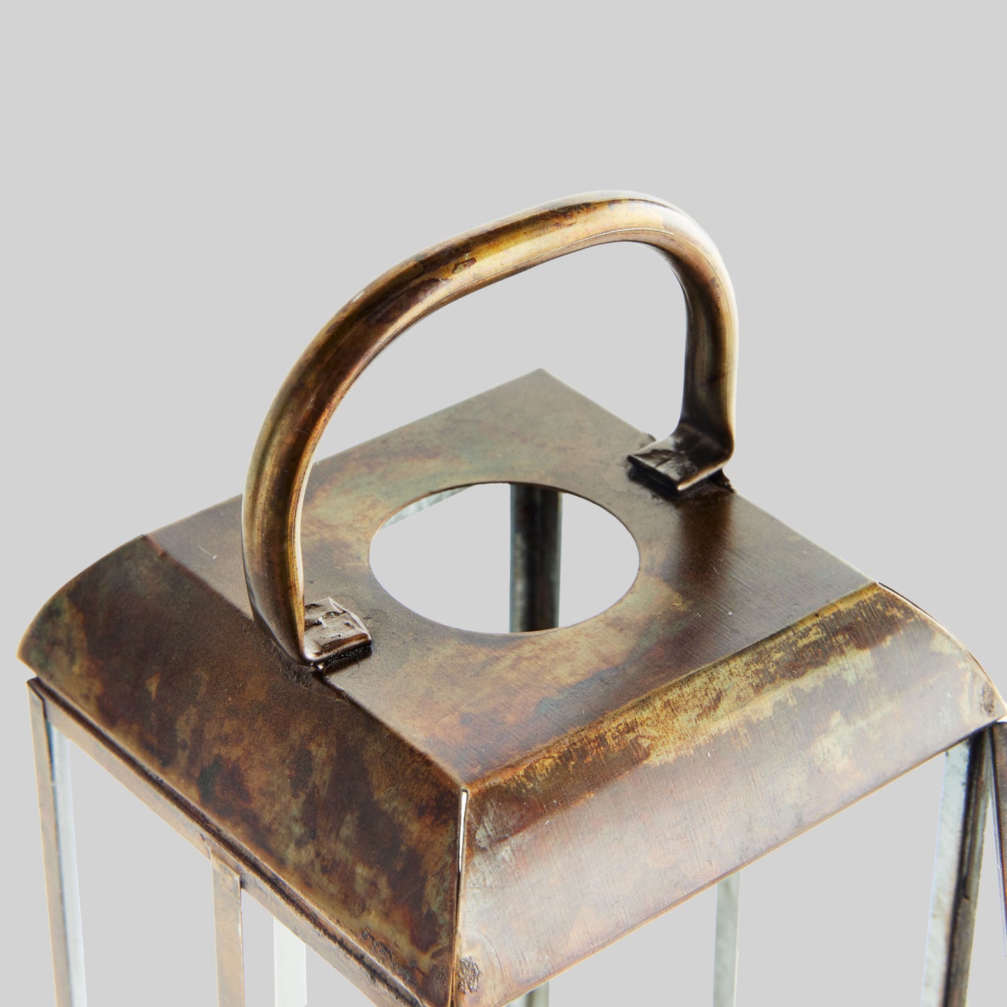 Closeup view of handle on antique brass tall lantern with gray background.