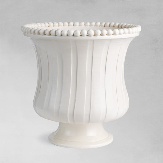 Beaded white flared ceramic vase with gray background.