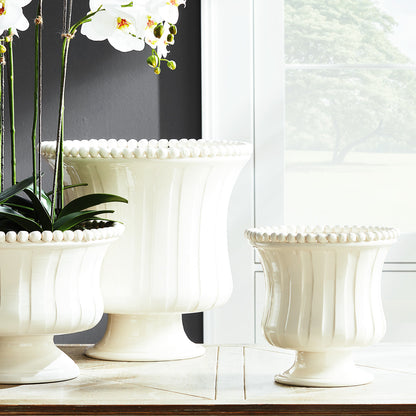 Set of three beaded white flared ceramic vases on wooden table.