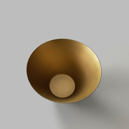 Inside of black and gold decorative metal bowl on gray background.