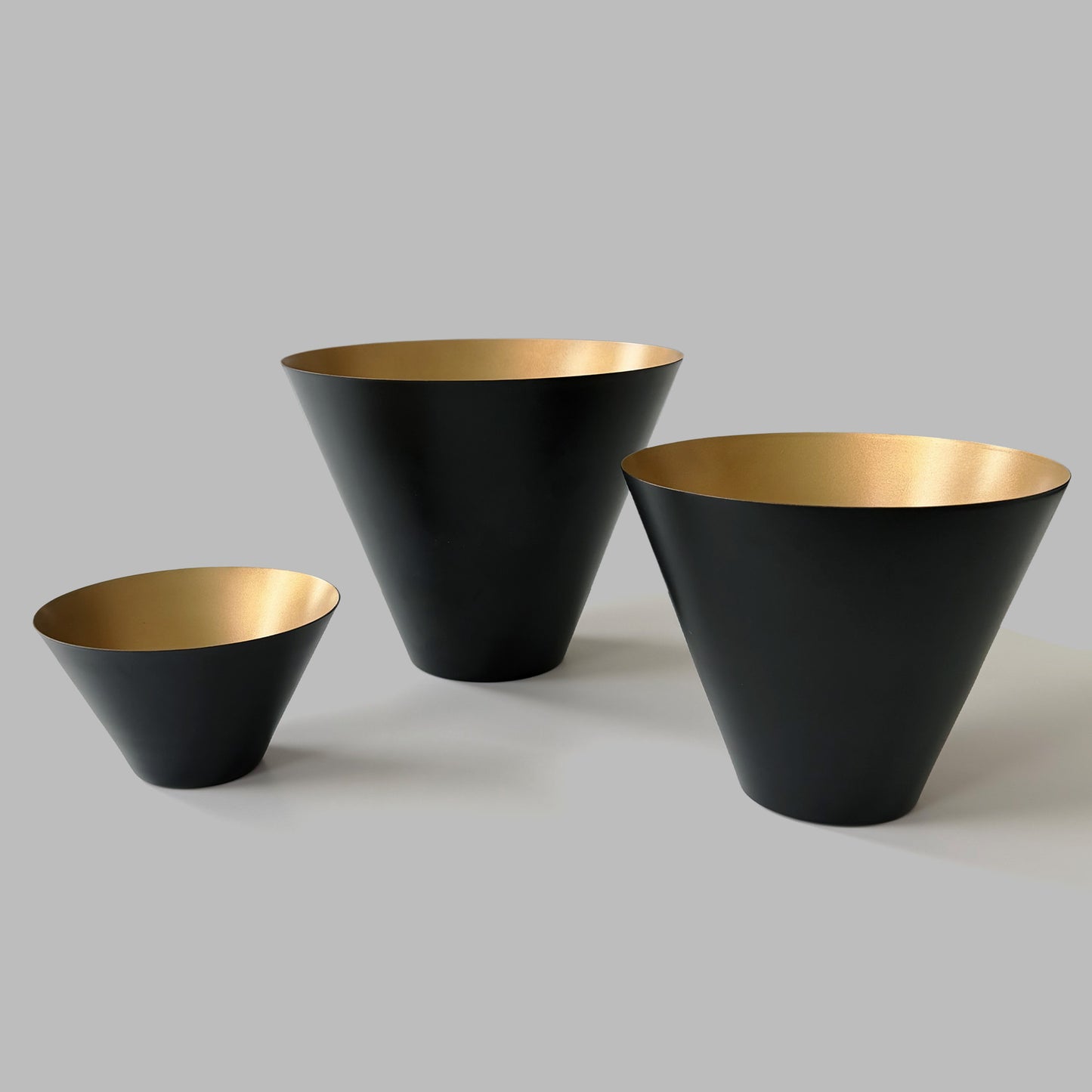 Black and gold decorative metal bowls with gray background.