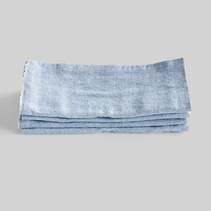 Blue scalloped square cotton dinner napkins set of 4, stacked and folded, with gray background.