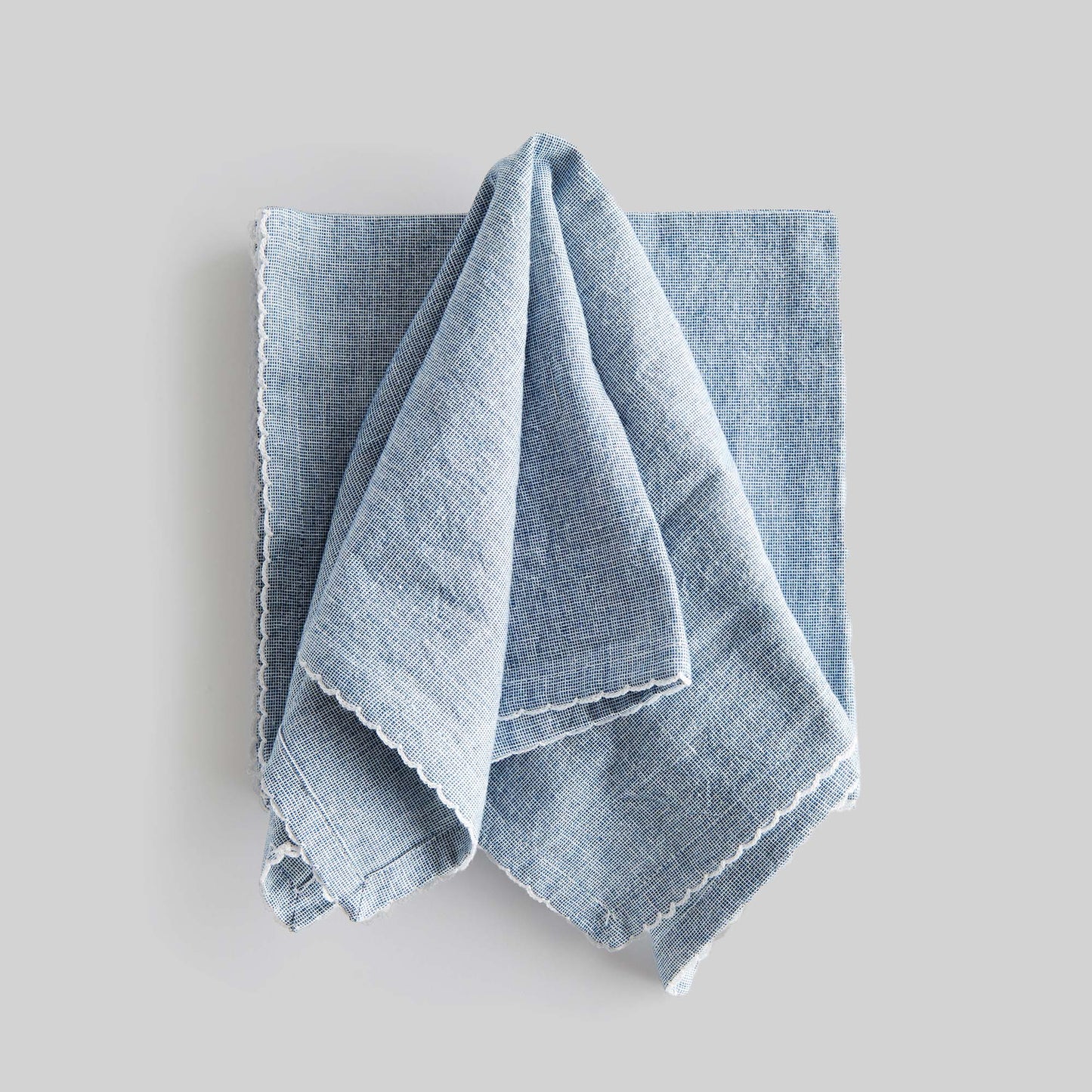 Blue scalloped square cotton dinner napkins set of 4 with gray background.