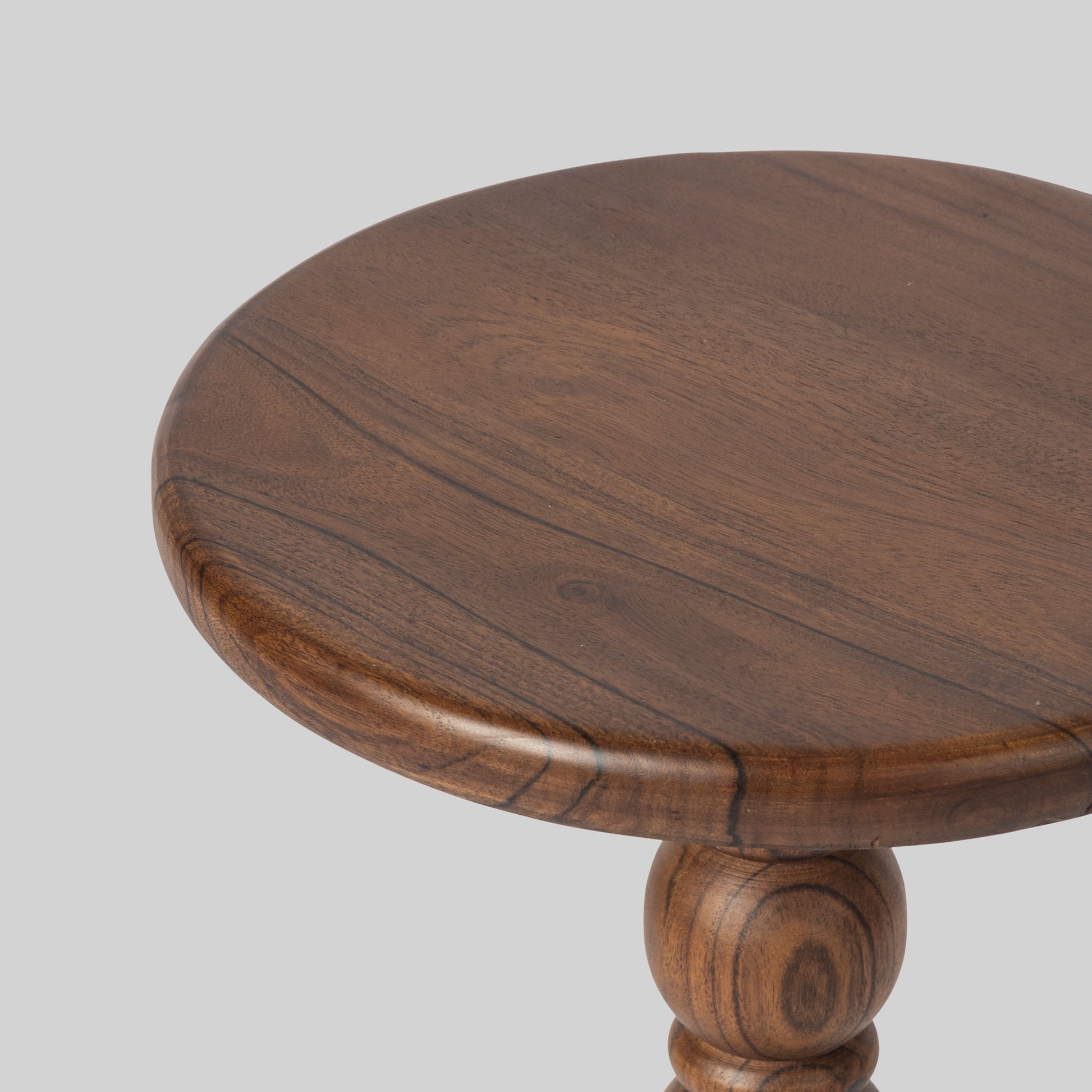Round wooden side table with spindle design on a light gray background.