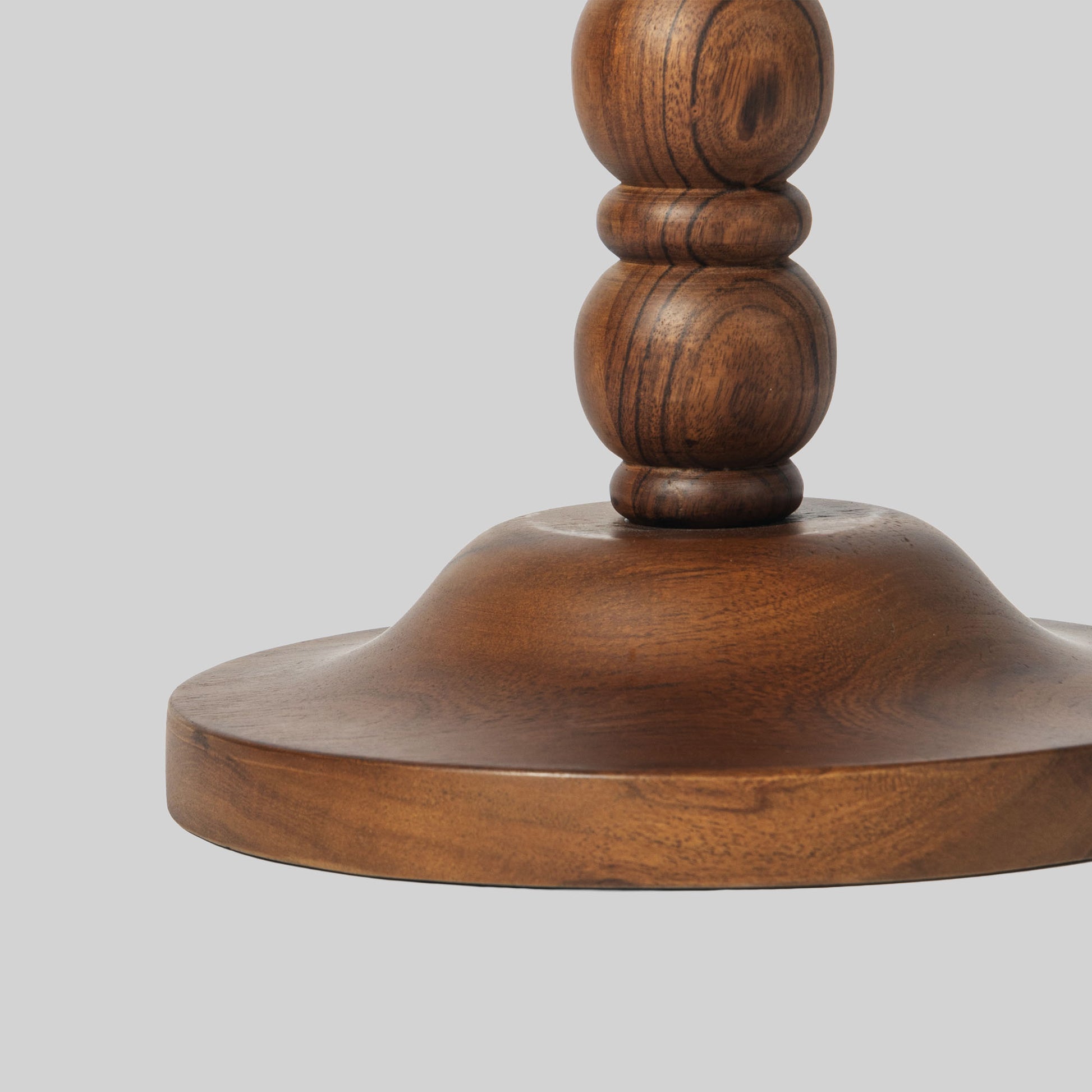 Round wooden side table with spindle design on a light gray background.