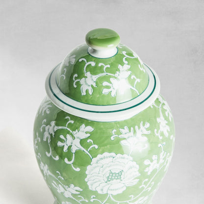 Chinoiserie green and white medium porcelain ginger jar, closeup view of top, with gray background.