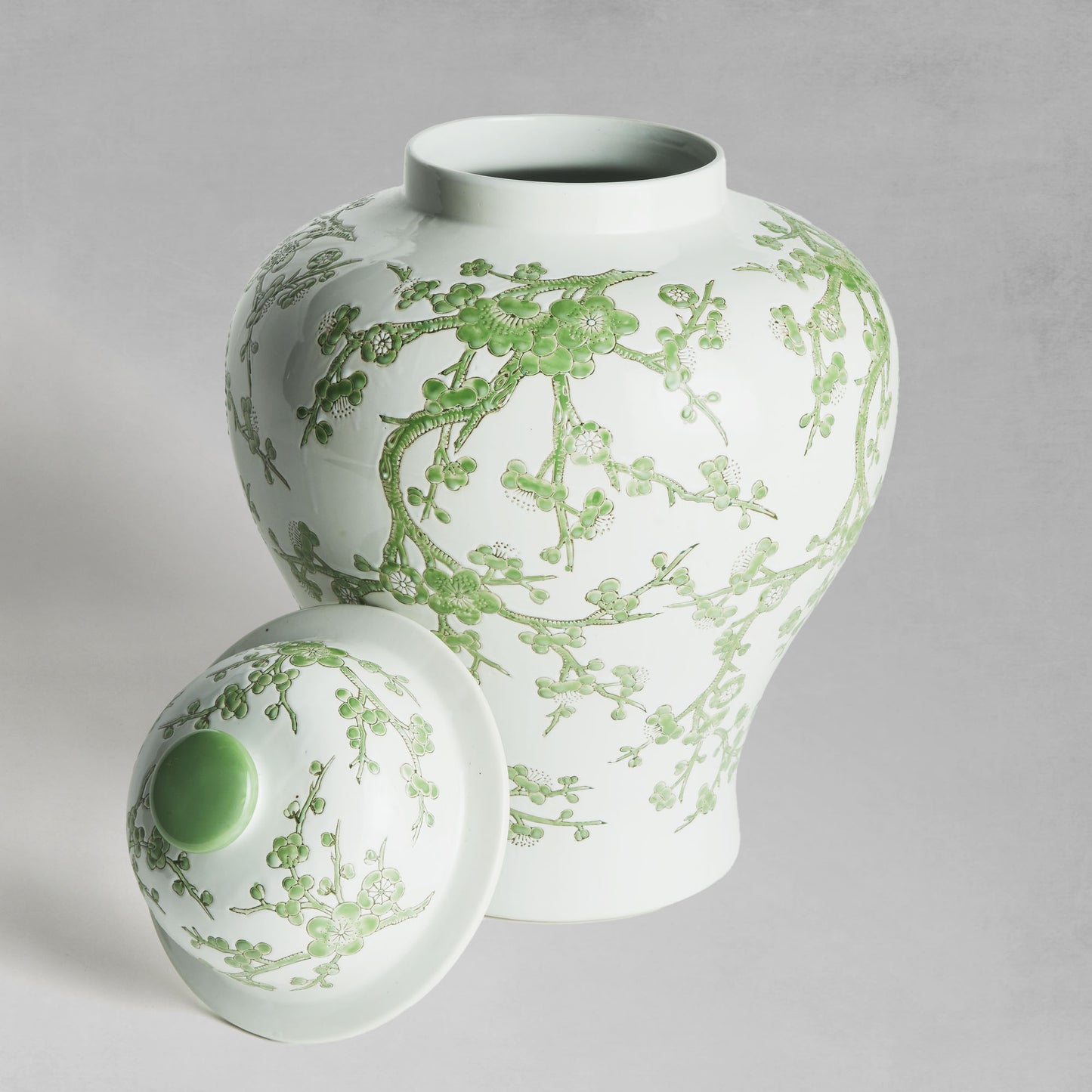 Chinoiserie green and white porcelain ginger jar, with lid removed, with gray background.