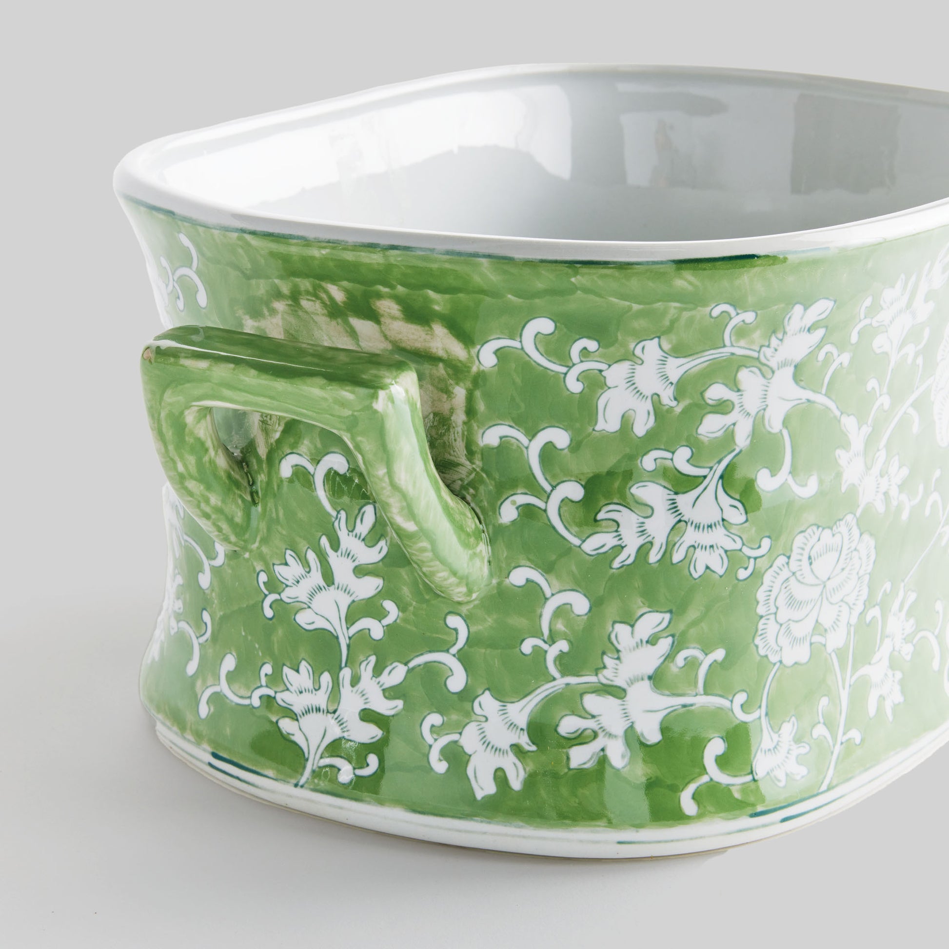 Chinoiserie green and white porcelain planter, handle closeup view, with gray background.