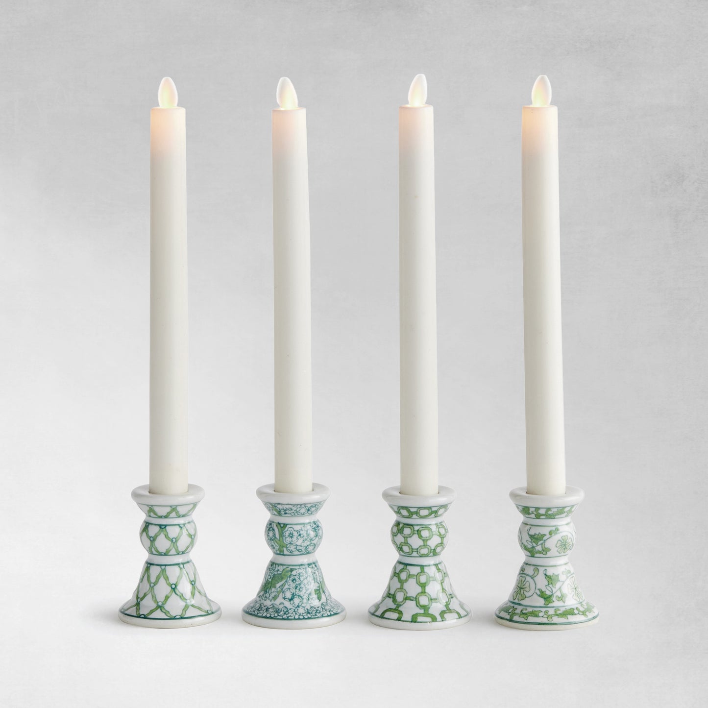 Set of 4 chinoiserie green and white porcelain taper holders with gray background.