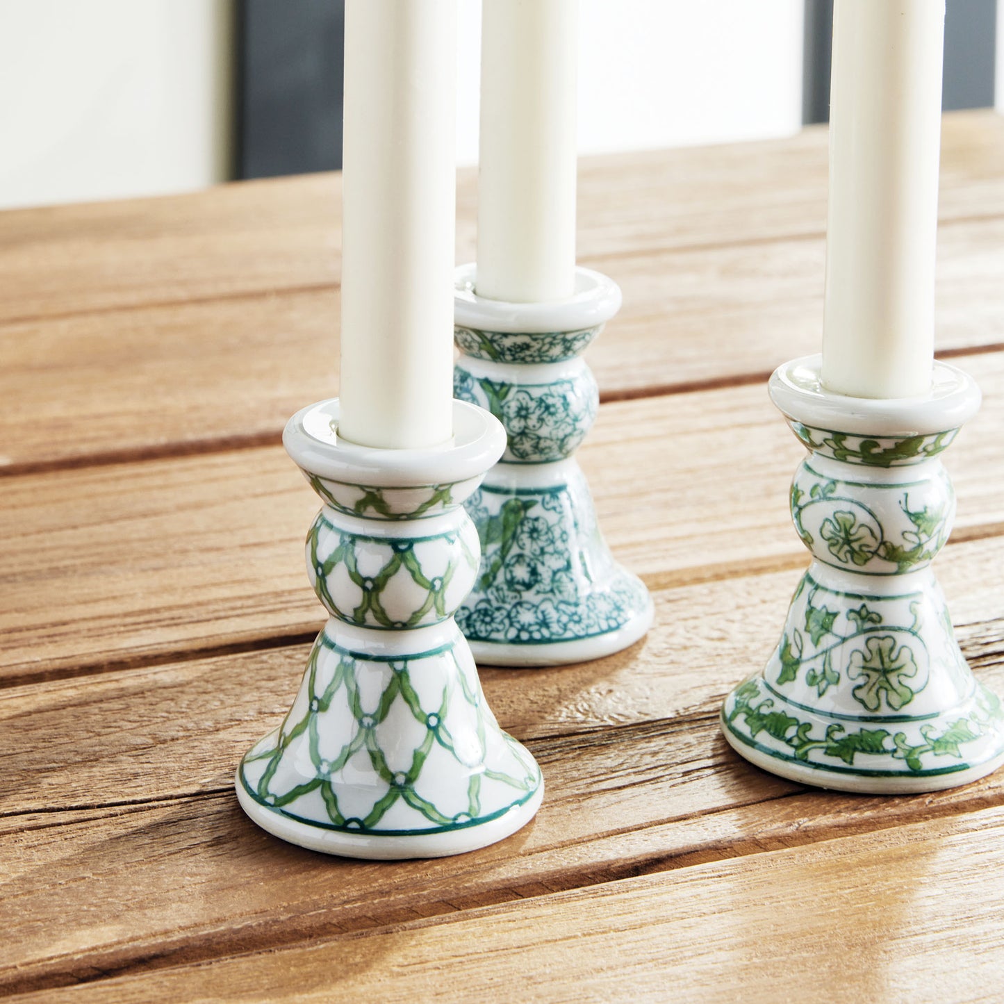 Chinoiserie green and white porcelain taper holders on teak outdoor dining table.