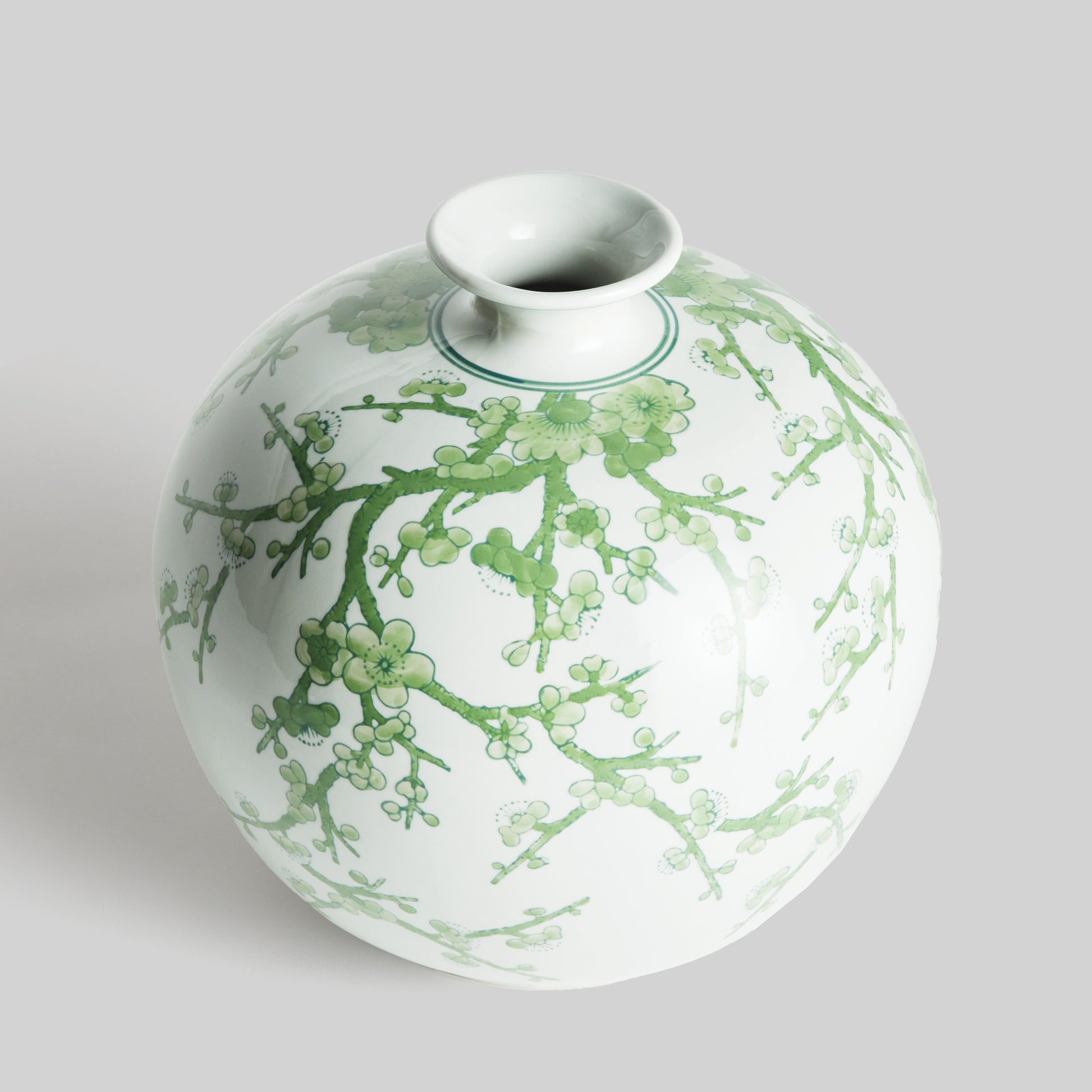 Chinoiserie green and white porcelain vase, angled top view, with gray background.