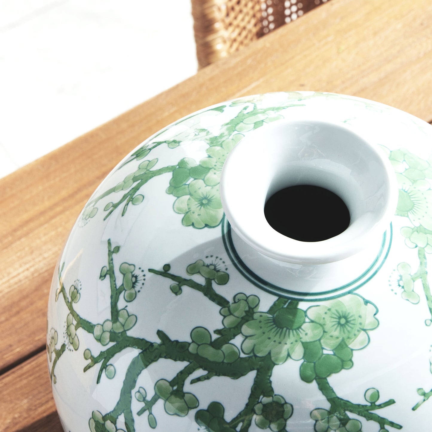 Chinoiserie green and white porcelain vase, closeup view of top, sitting on wood dining room table.