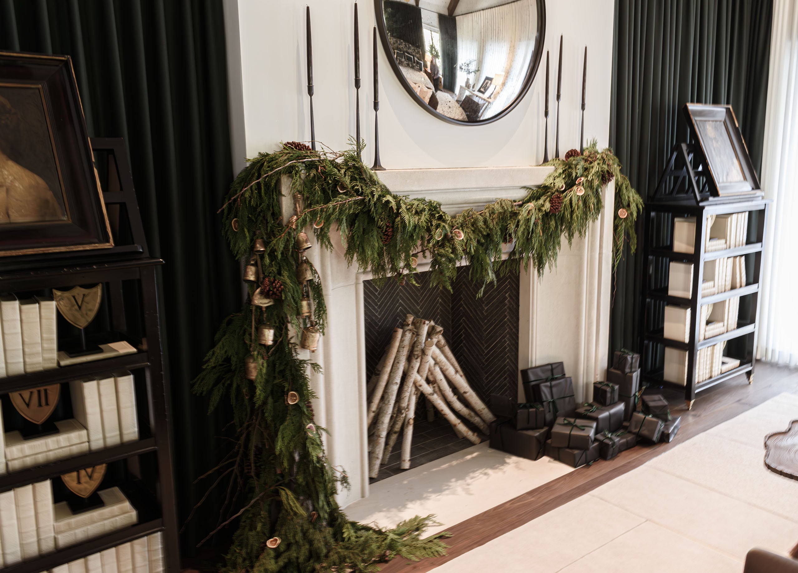 Living room fireplace mantel decorated with garland with Christmas presents in front of the fireplace.