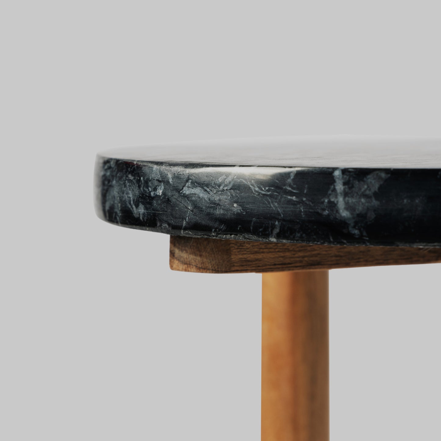 Contemporary acacia wood and black marble accent table, closeup view.