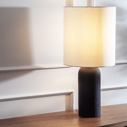 Contemporary black textured table lamp stylized and illuminated on console table.