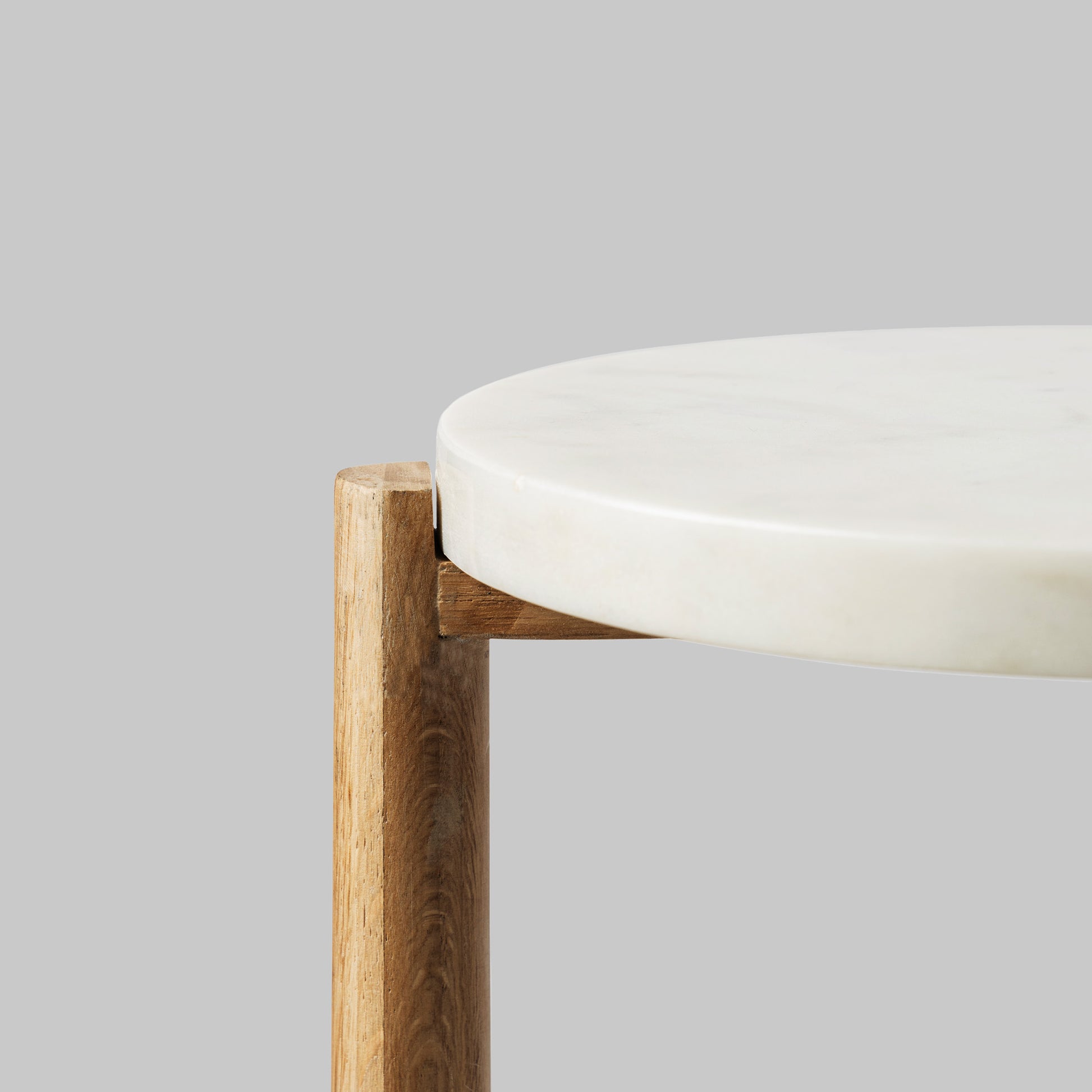 Contemporary oak wood and white marble accent table, closeup view.