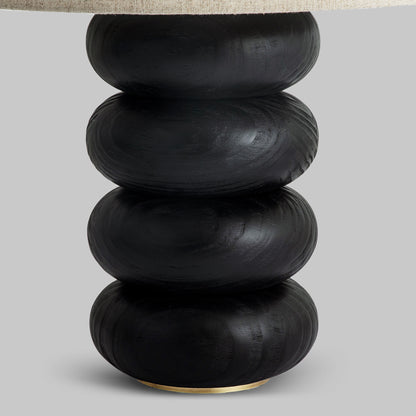 Contemporary stacked wood ring table lamp with black finish, closeup view of lamp.