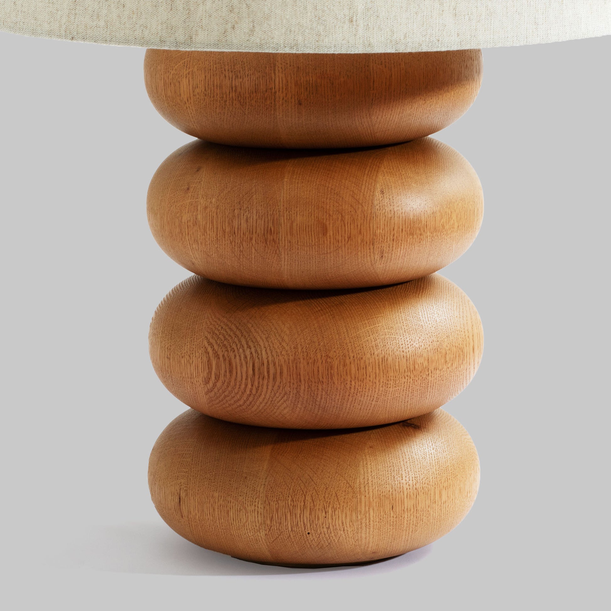 Contemporary stacked wood ring table lamp with natural finish, closeup view.