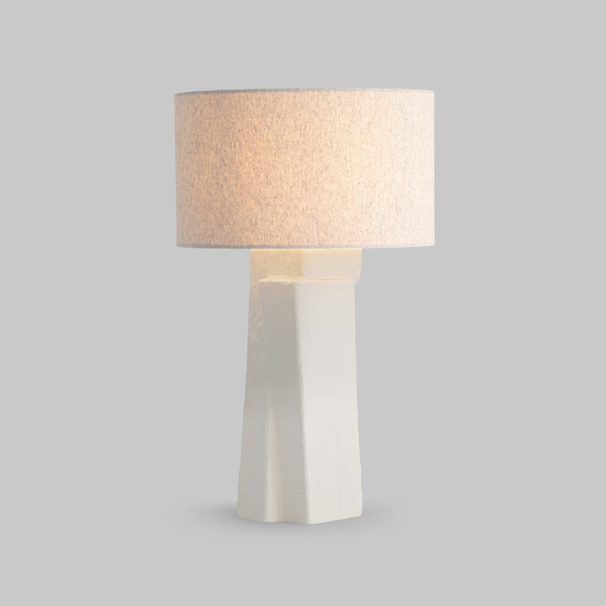 Contemporary white plaster table lamp, illuminated.