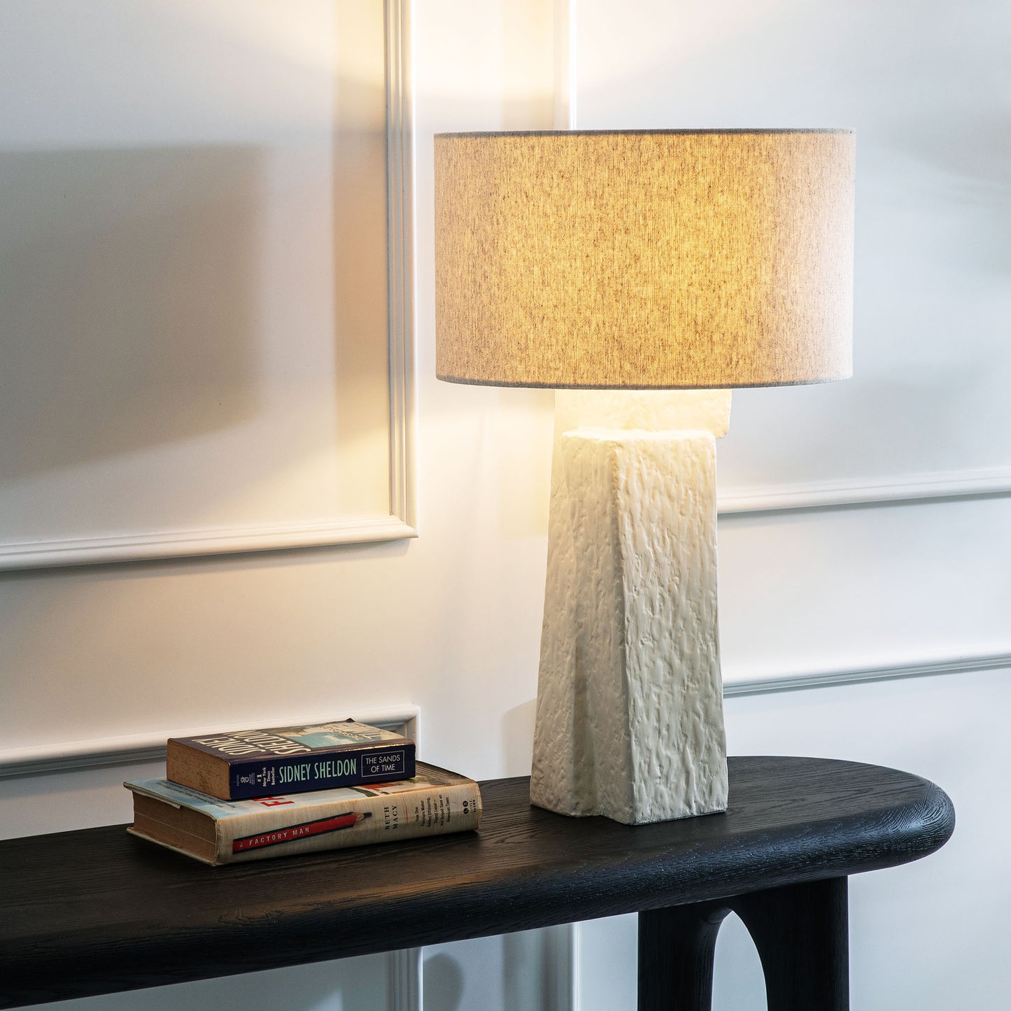 Contemporary white plaster table lamp stylized on console table.