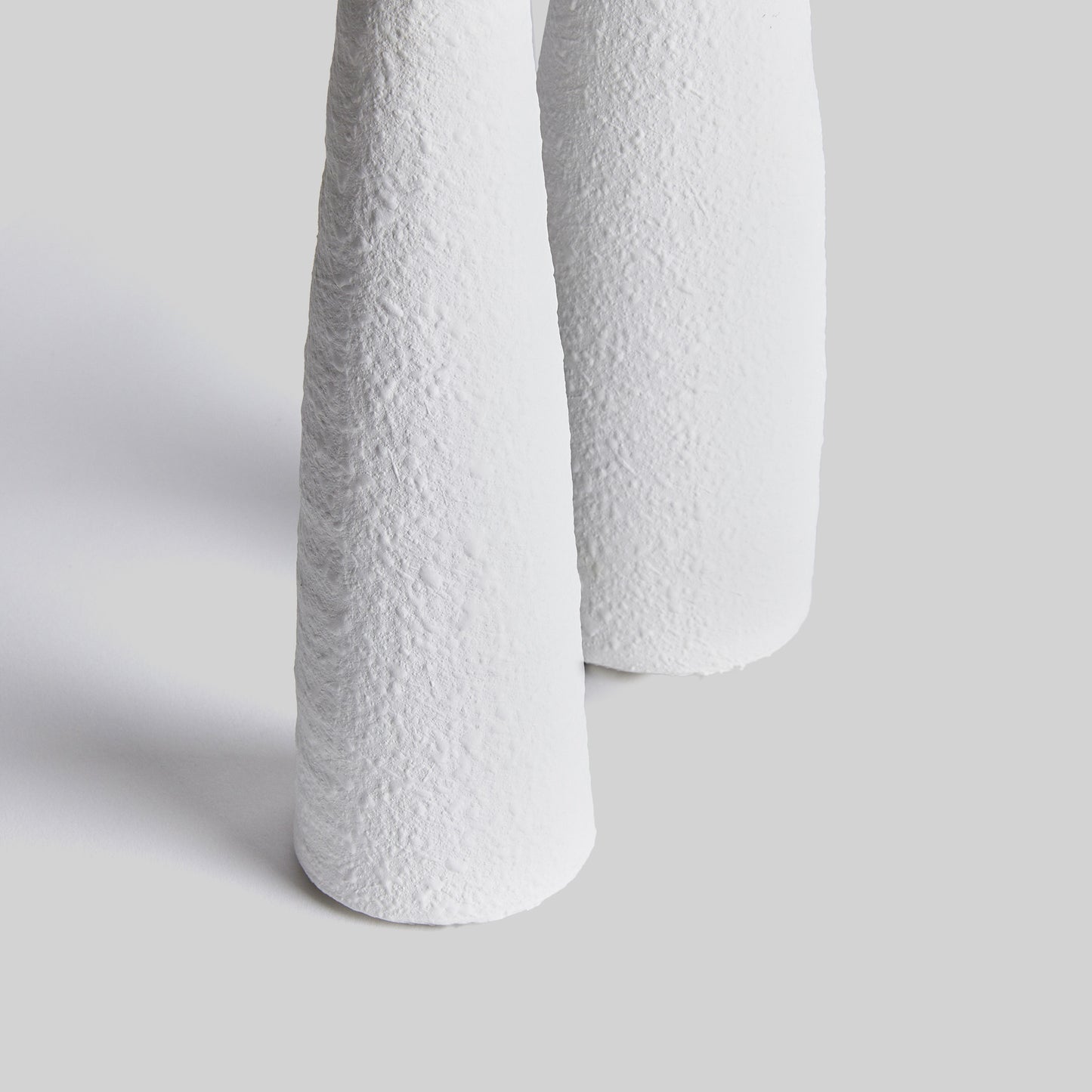 Closeup view of contemporary white terracotta candleholders, set of 2, with gray background.