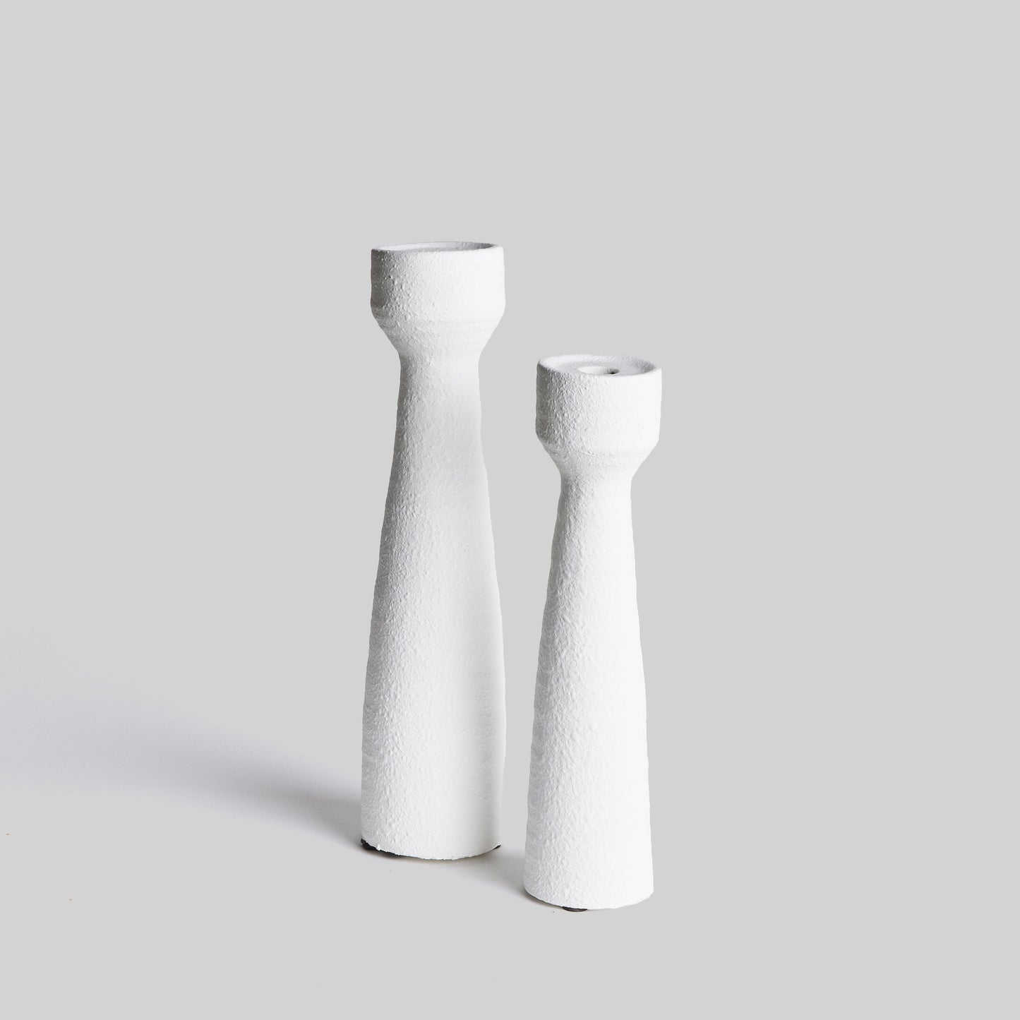 Contemporary white terracotta candleholders, set of 2, with gray background.