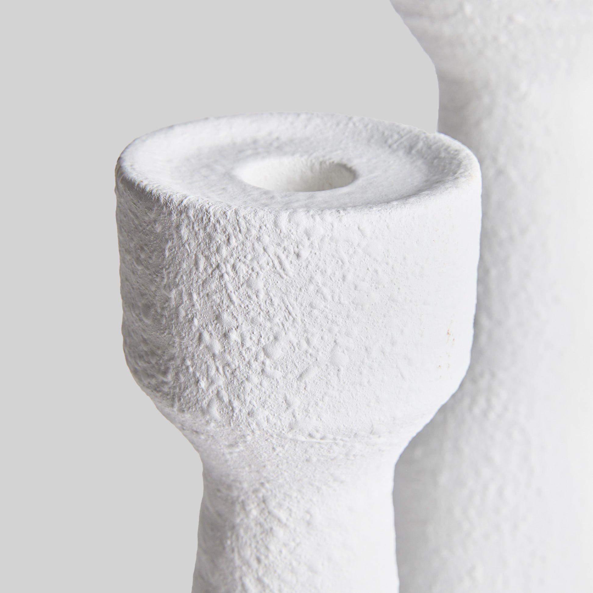 Closeup view of contemporary white terracotta candleholders, set of 2, with gray background.