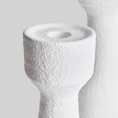 Closeup view of contemporary white terracotta candleholders, set of 2, with gray background.