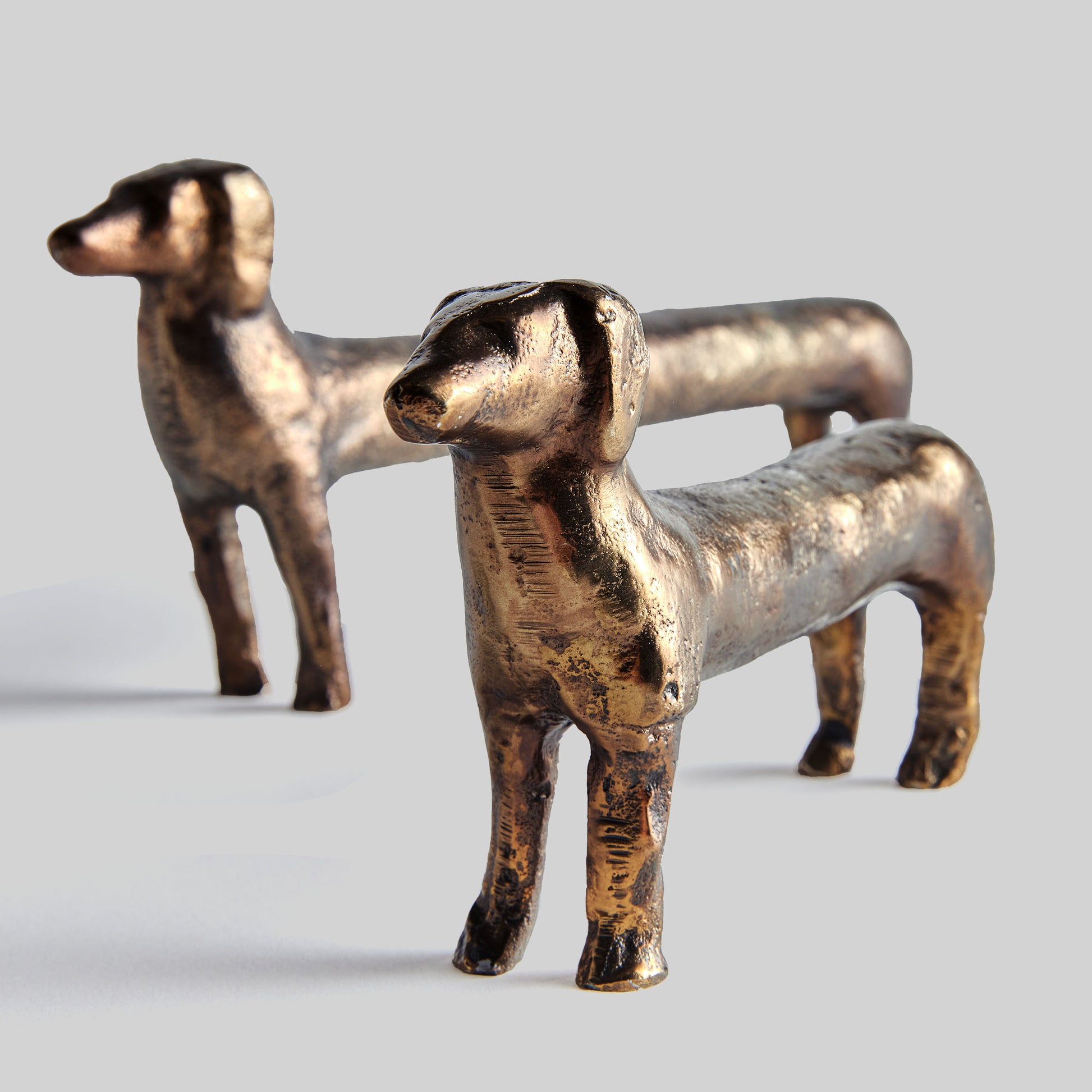 Closeup view of Dachshund decorative objects with antique brass finish, set of 2, with gray background.