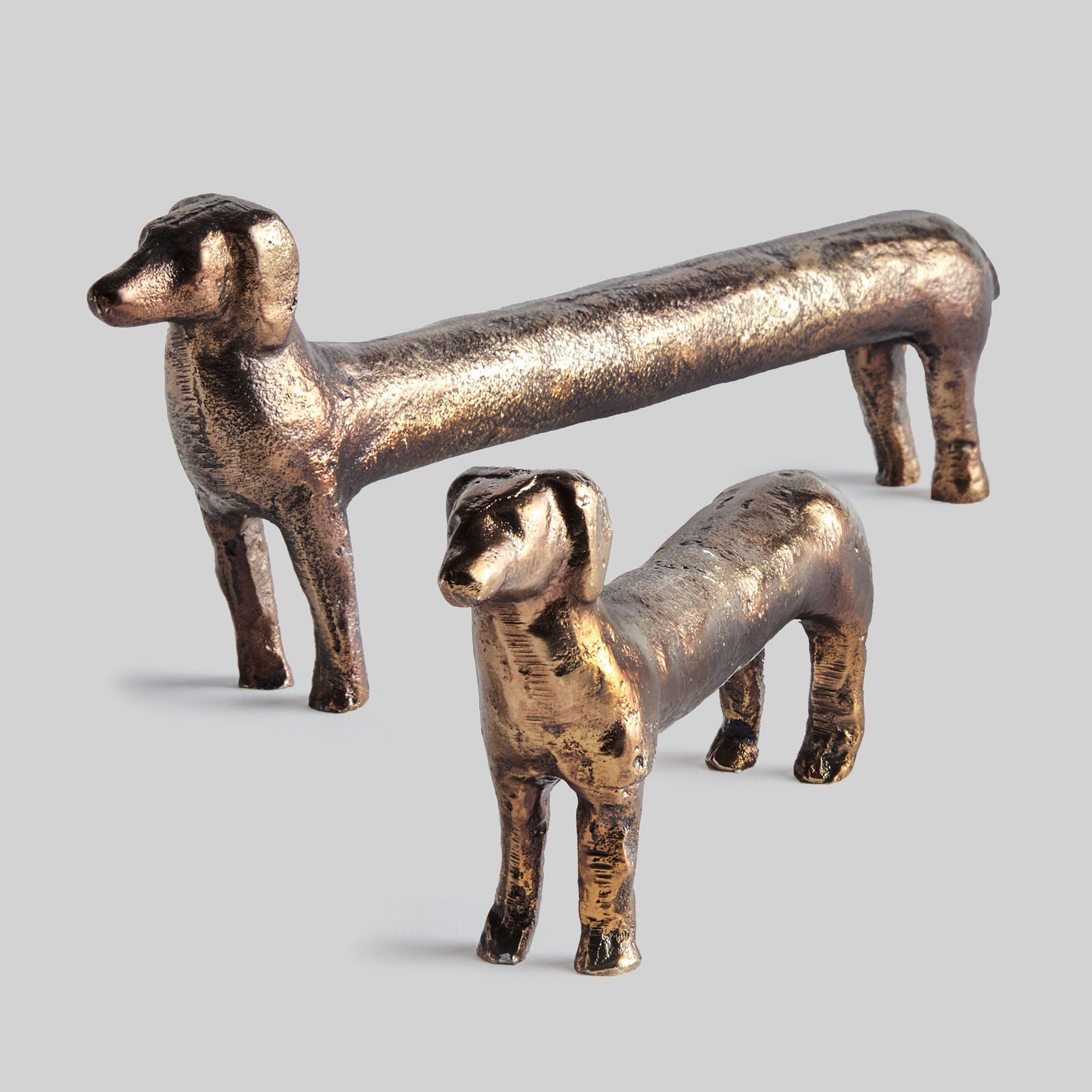 Dachshund decorative objects with antique brass finish, set of 2, with gray background.