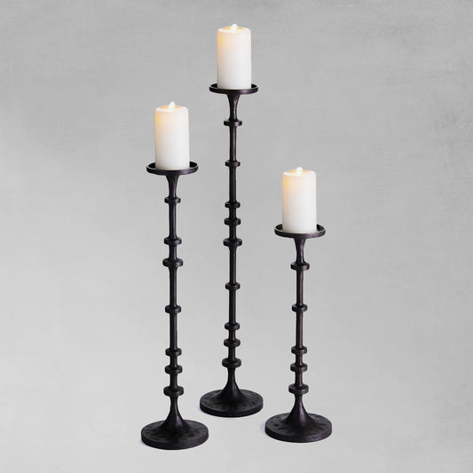 Dark bronze aluminum pillar candleholders with gray background.