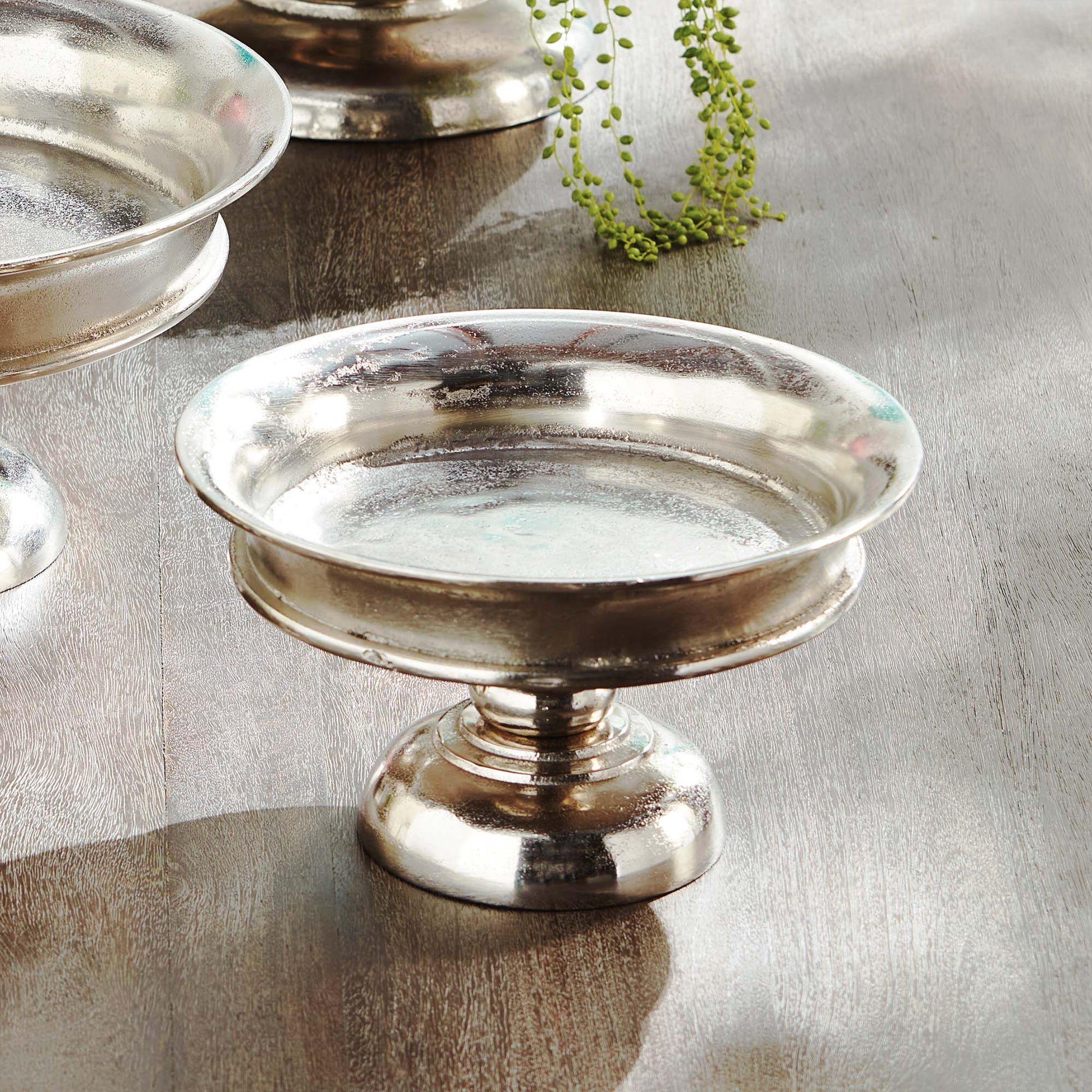 Decorative brushed nickel pedestal stylized on table.