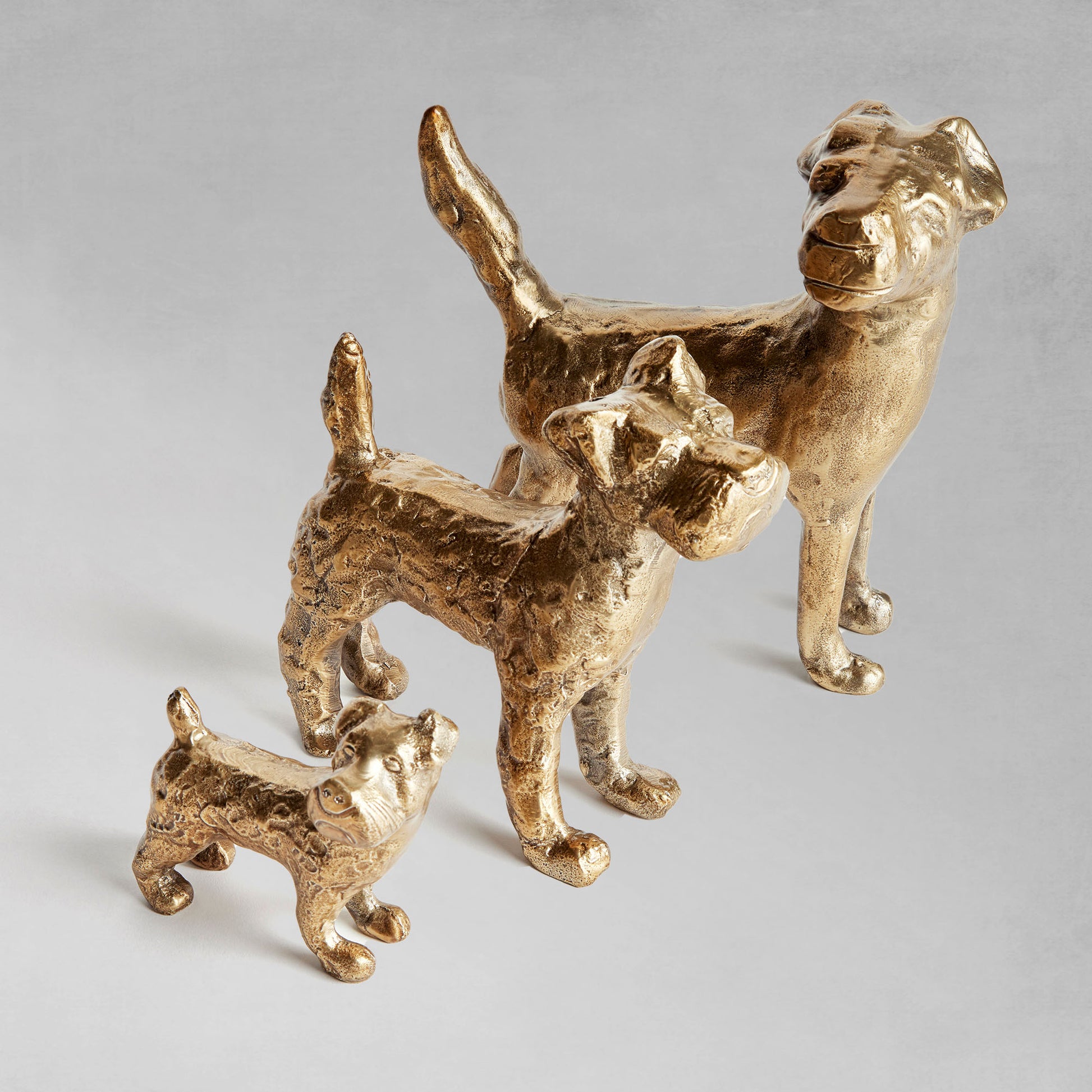 Decorative dog objects, set of 3, lined up with gray background.