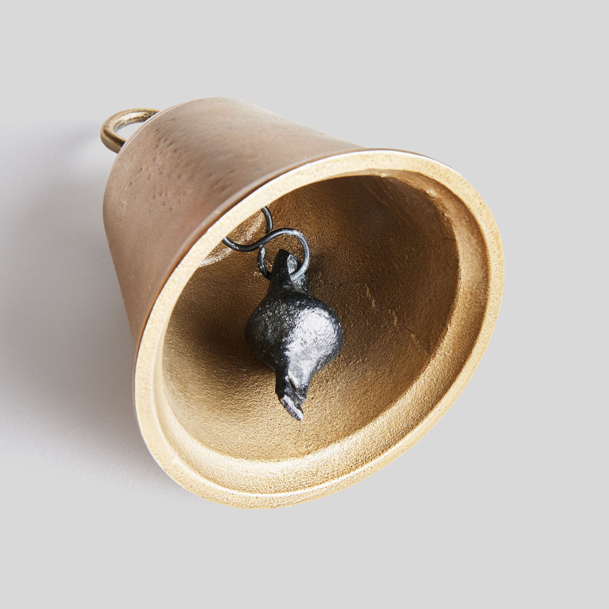 Decorative gold bells, set of two, closeup view of inside of bell, with gray background.