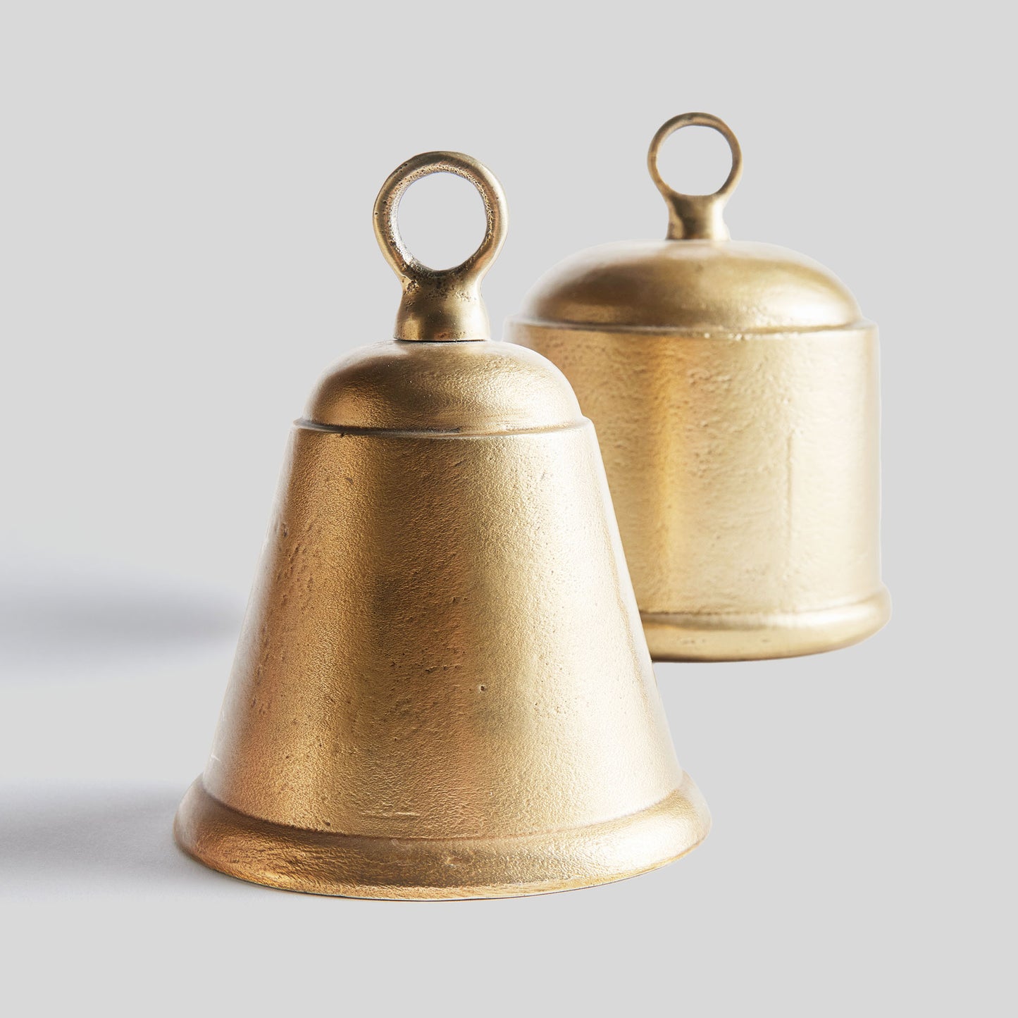 Decorative gold bells, set of two, with gray background.