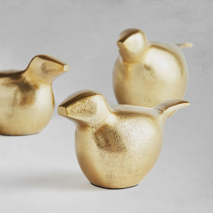 Decorative gold bird objects, set of 3, closeup view, with gray background.