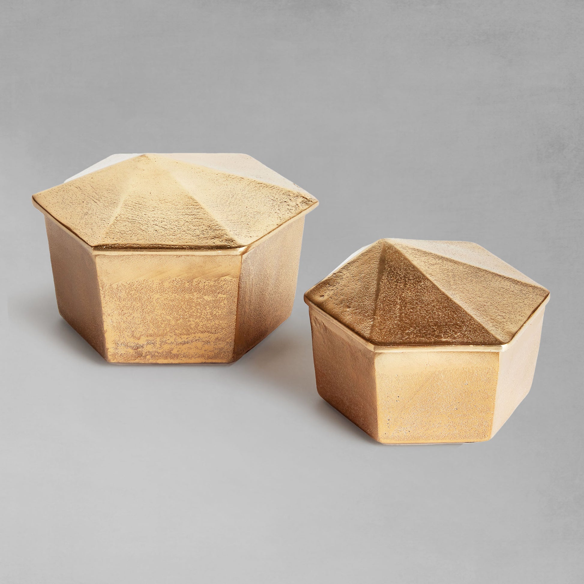 Decorative gold geometric lidded boxes with gray background.